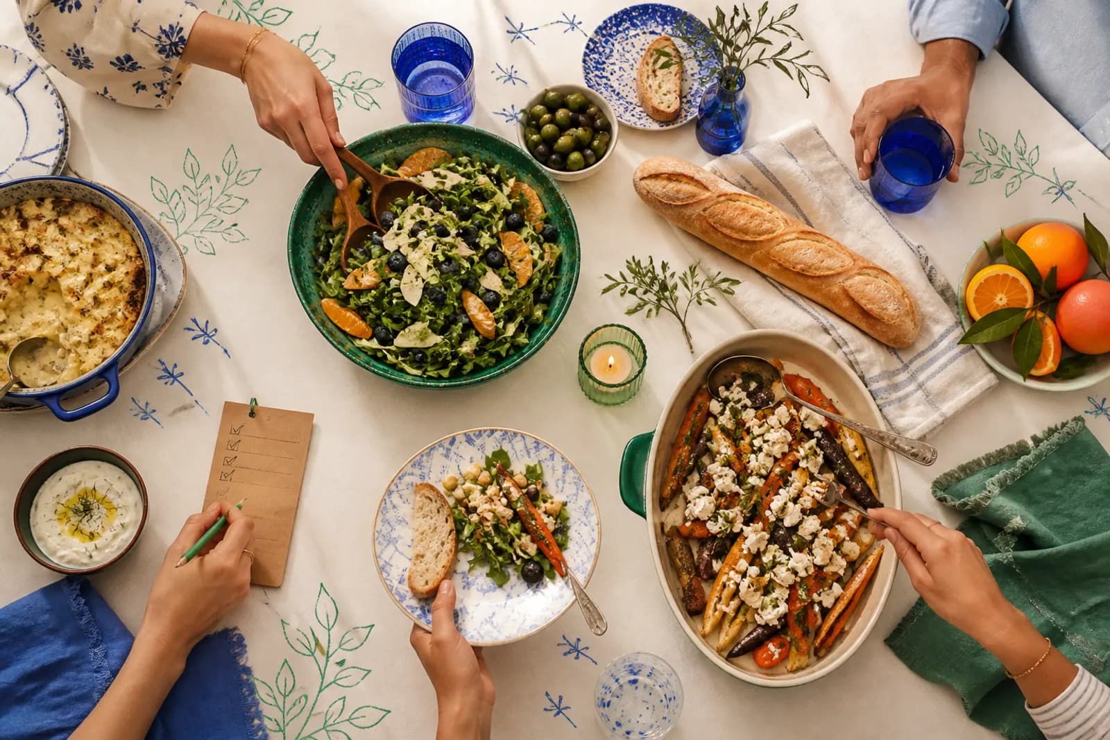 A potluck table with shared dishes, napkins, and a small checklist